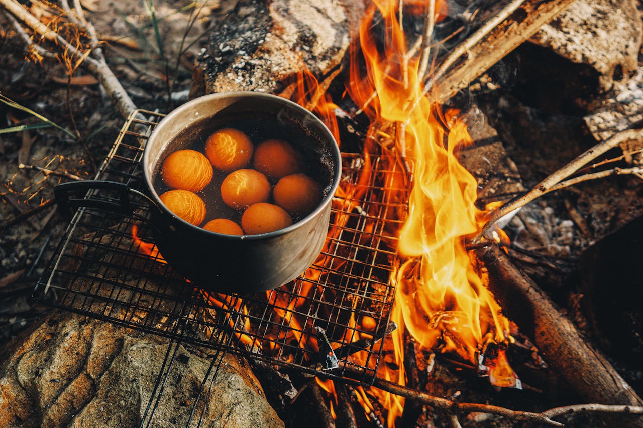 Pot with eggs boiling over a campfire in Tây Ninh, Vietnam. Rustic outdoor cooking scene.